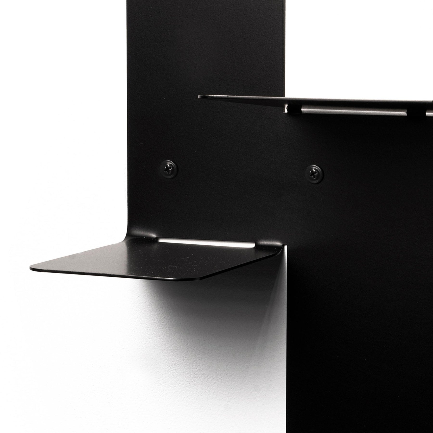Close-up of a contemporary black metal floating platform with visible hardware and dual-tiered surfaces.