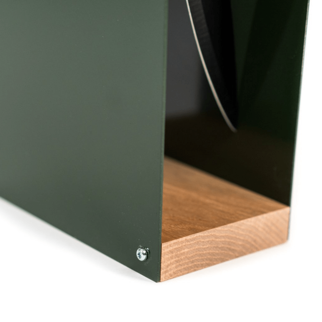 Close-up of a green knife block with a natural wood base and a visible side slot holding a knife. The smooth wooden grain contrasts with the matte green metal, displayed against a white background.