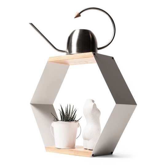 Hexagonal shelf with powder-coated metal sides and natural wood surfaces, holding a metal watering can on top and a potted succulent with a white sculpture on the lower surface.