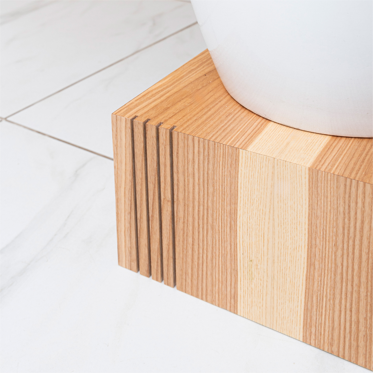 Wooden cube plant stand in ash wood finish with vertical grooves on one corner 