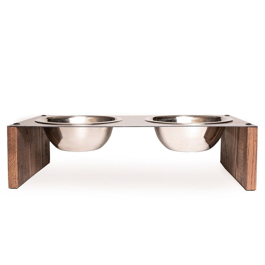Front view of an elevated pet feeder with two stainless steel bowls set in a metal top, supported by wooden side panels.