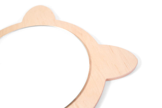 Close-up side view of a cat-shaped wooden mirror, featuring smooth, layered wood with a natural grain and a round reflective surface.